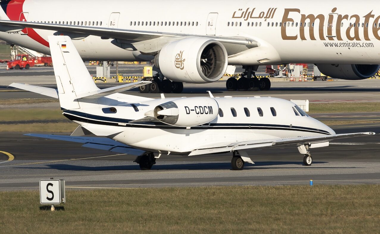 Cessna Citation XLS+ D-CDCM on a taxiway, with an Emirates aircraft in the background.