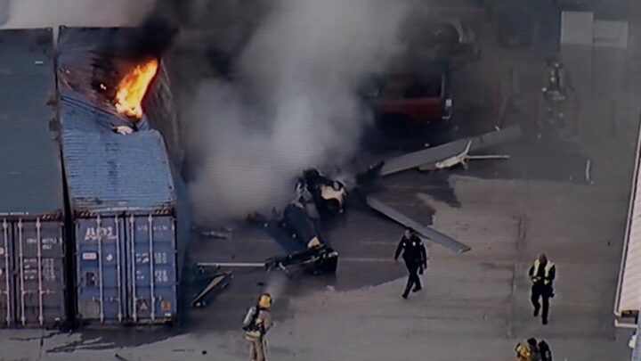 Photo showing the crashed helicopter in flames after crashing into containers.