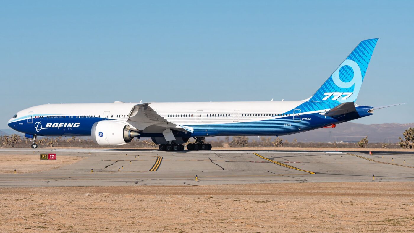 Boeing 777-9 N779XW in blue and white Boeing livery on the ground, viewed from the side.