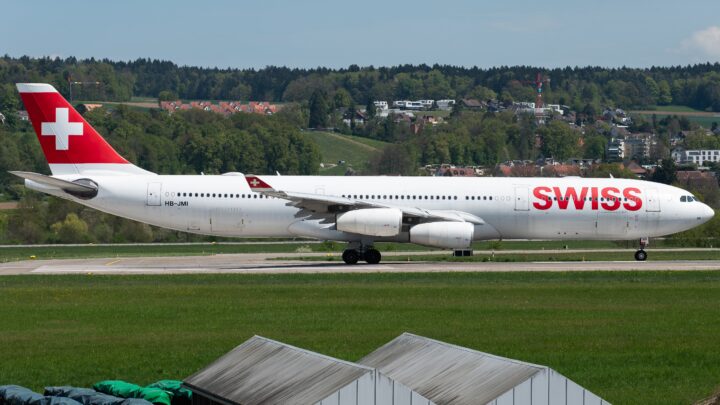 Side view of SWISS Airbus A340-300 HB-JMI on a taxiway, with a white fuselage and red Swiss-cross tail.