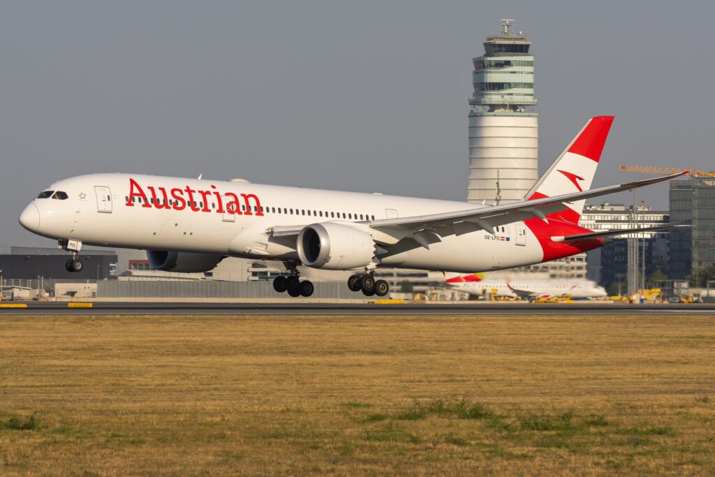 Austrian Airlines Boeing 787-9 OE-LPG approaching touchdown with the airport control tower behind it.