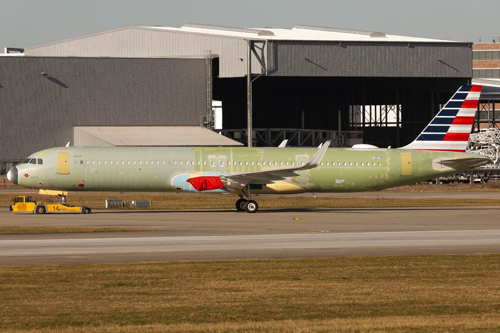 Unfinished Airbus A321neo with an American Airlines tail being towed, with green primer visible and engines not yet installed.