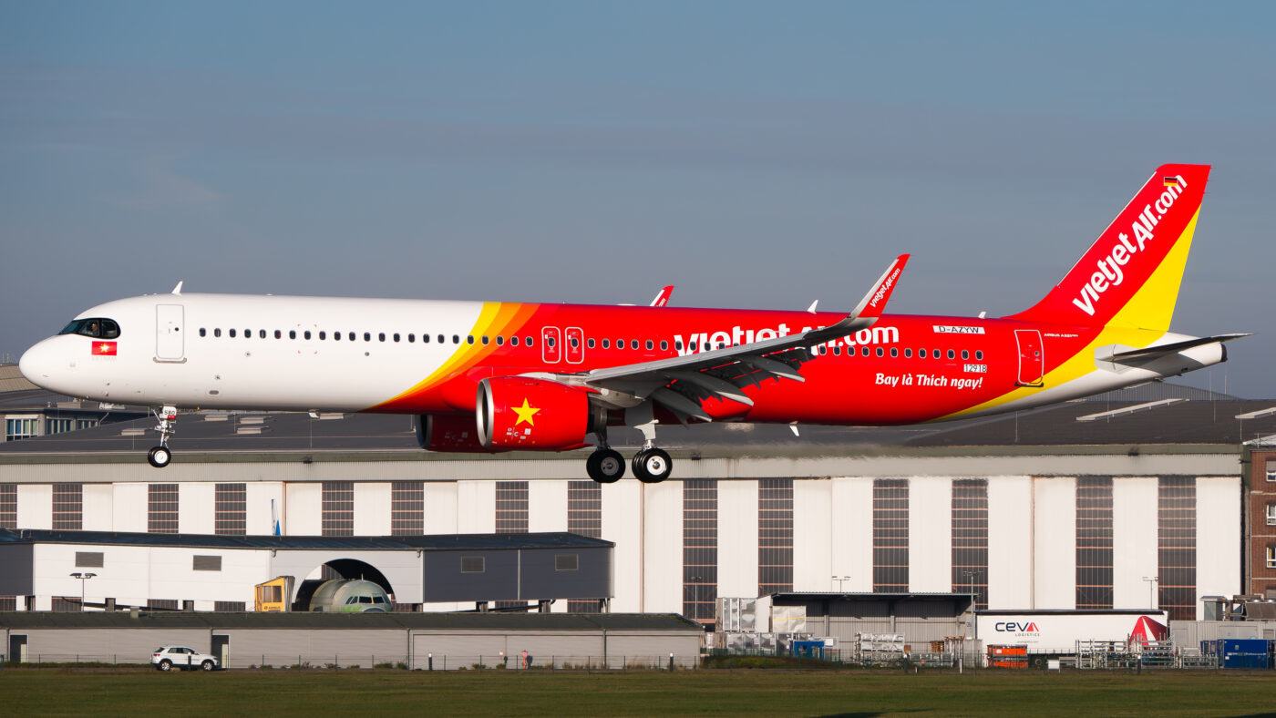 VietJet Air Airbus A321neo in its distinctive red and yellow livery, photographed in flight with its landing gear extended.
