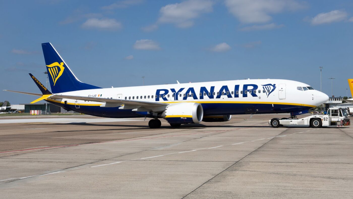 Ryanair Boeing 737 MAX 8, registered EI-IJG, on an airport apron with a pushback tug connected to its nose gear.